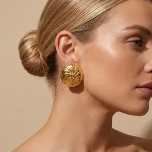 Detailansicht eines goldenen Edelstahl-Ohrsteckers mit Spirale am Frauenohr