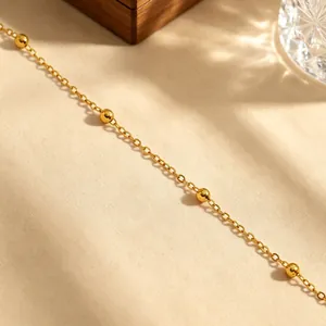 Makro-Detailansicht einer minimalistischen Goldkette mit polierten goldenen Perlen
