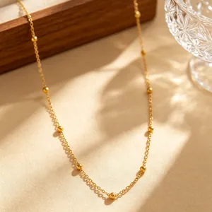 Detailansicht einer minimalistischen goldenen Satellitenkette mit eleganten Perlen.