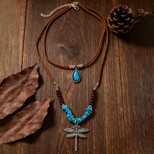 Detail van de bohemian gelaagde turkooizen ketting met zilveren libel hanger op hout
