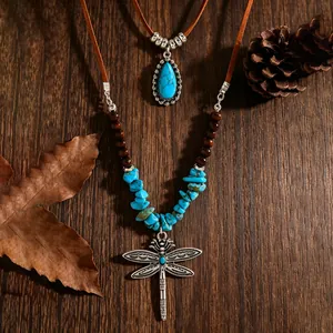 Gedetailleerde weergave van de vintage turquoise libelle ketting op rustiek houten blad.
