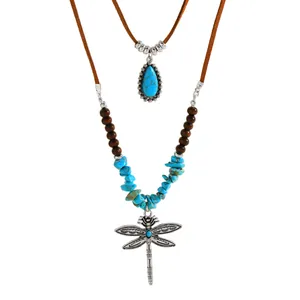 Detailweergave van zilveren libelle hanger en turquoise stenen op de etnische ketting