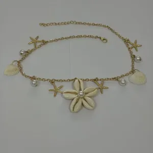 Dettaglio della collana dorata in stile spiaggia con conchiglie e perle bianche
