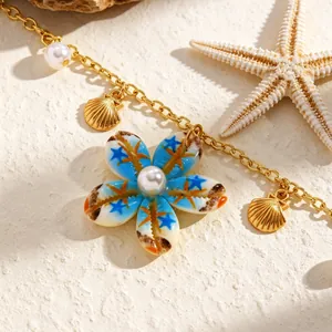 Dettaglio macro di collana stile spiaggia con fiore in conchiglia blu e perle finte