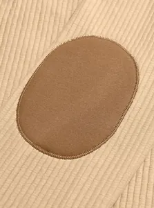 Macro view showing ribbed knit fabric texture and brown oval elbow patch on men's sweatshirt