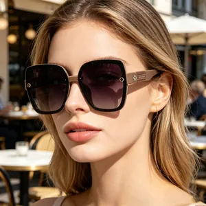 Detail of oversized polarized sunglasses on model in a chic outdoor cafe setting