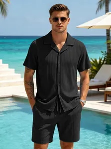 Full view of a man wearing a black textured short sleeve shirt and shorts set by the pool.