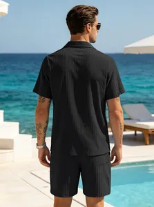 Back view of a man in a black textured short sleeve vacation set by a resort pool