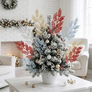 Ramoscelli di foglie glitterate in un albero di Natale innevato per decoro festivo.