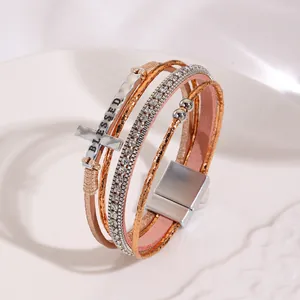 Close-up of Bohemian multi-layer leather bracelet with cross charm and magnetic buckle