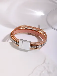Detailed view of bohemian multilayer leather bracelet with rhinestones and cross charm