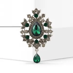 Close-up of a vintage emerald green glass pendant brooch featuring grey crystal accents