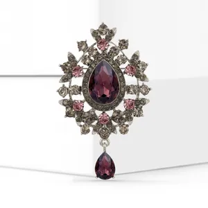 Close-up of a vintage brooch with purple pear-cut glass and dangling pendant.