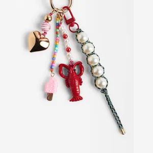 Bijou de sac coloré avec cœur doré, homard rouge et détails en perles