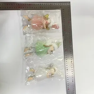 Detailed view of three Christmas angel doll ornaments measured with a ruler for scale.