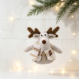 Plush reindeer Christmas ornament hanging on a pine branch with warm lights