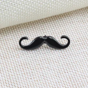 Close-up detail of a shiny black enamel mustache brooch lapel pin on white fabric