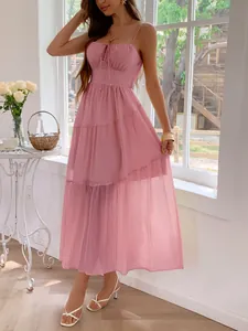 Full-length view of an elegant pink tiered maxi dress on a model in a sunlit room.