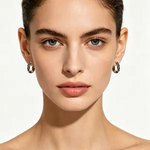 Elegant leopard pattern cubic zirconia hoop earrings in gold plating on model face.