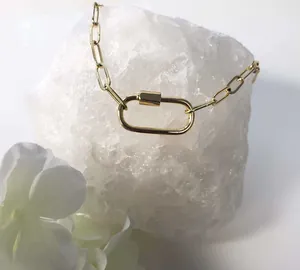 Detailed view of a gold-plated stainless steel carabiner clasp on a link chain necklace.