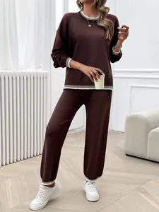 Detail view of a loose brown long-sleeve knit two-piece set with white striped trim.