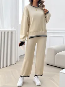 Full body detail of women's beige oversized two-piece knit set with black striped trim
