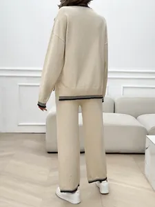 Rear view of a beige knit two-piece set featuring black striped cuff and hem details.