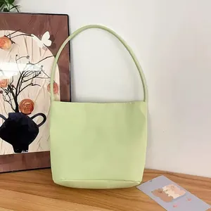 Detailansicht einer minimalistischen hellgrünen Nylon-Schultertasche auf Holz.