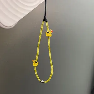 Detailed macro view of yellow frosted glass beads and cute duck charms on phone strap
