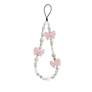 Détail de la dragonne de téléphone avec nœud rose et perles d'imitation irrégulières