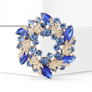 Détail macro montrant les cristaux bleus et la finition dorée de la broche couronne chic