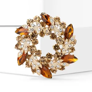 Détail d'une élégante broche couronne dorée ornée de strass ambre et transparents