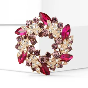 Détail de la broche couronne en strass roses avec des motifs de feuilles dorées élégantes