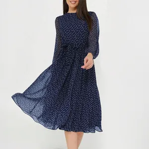 Robe mi-longue élégante bleu marine à pois avec manches transparentes et jupe fluide.