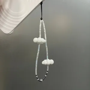 Close-up of white cloud charms and gradient beads on a stylish mobile phone strap.