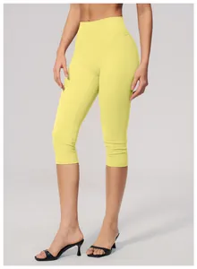 Detailed macro view of yellow high-waisted brushed yoga capris for fitness and sport.
