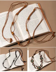 Macro view of bohemian handmade woven waist chains with wooden beads on vintage books.