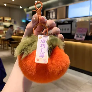 Close-up of soft orange plush persimmon keychain featuring a success blessing tag