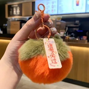 Detailed view of soft plush persimmon keychain with good luck blessing tag in hand