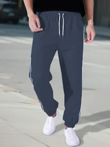 Close-up of the elastic cuff and side stripe detail on navy blue windbreaker pants