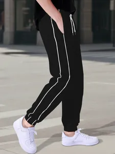 Detail view of black high street jogger pants with double white side stripes