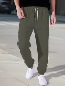 Detailed side view of men's army green parachute pants featuring white side stripes and drawstrings