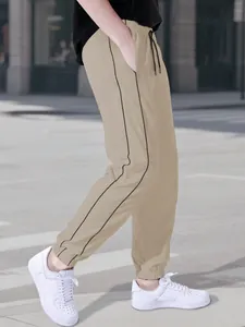 Side view of men's beige parachute pants with black stripes and elastic cuffs