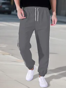 Outdoor street style view of men's gray high street sports joggers with white stripes