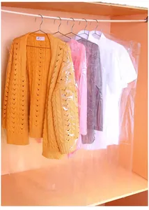 Transparent hanging plastic garment bags protecting clothes in a wooden closet.