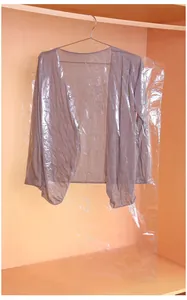 Transparent plastic garment dust cover over a grey cardigan in a wooden closet.