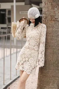 Detail of white crochet floral lace mini dress featuring flared sleeves and a round neck