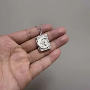 Silver book-shaped locket necklace with embossed cat on moon design in hand