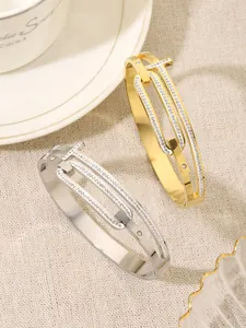 Detailed view of gold and silver T-shaped titanium steel bangles with sparkling stones