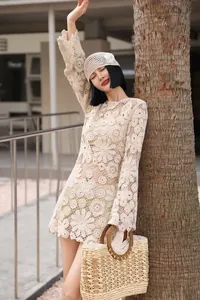 Close-up of a French style cream lace A-line dress with flared sleeves and floral patterns.